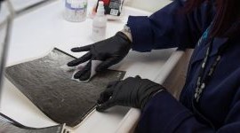 Person wearing gloves handling a document.