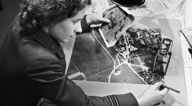 Monochrome image of a woman looking at aerial photographs.